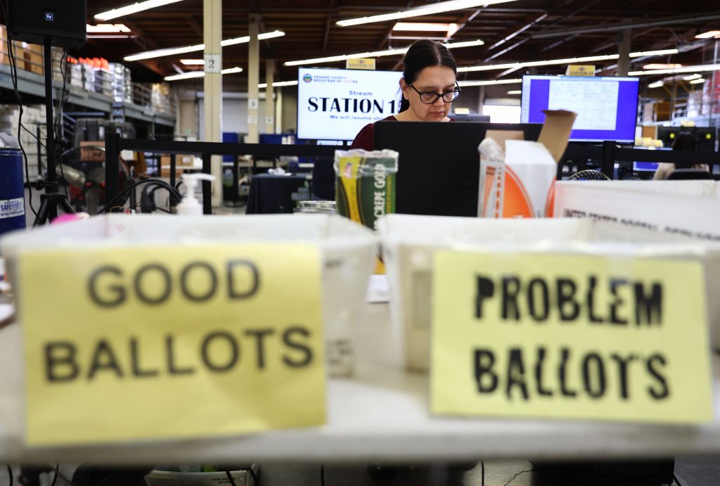 a ballot official behind boxes marked good ballots and problem ballots